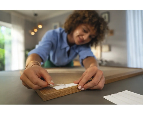 Vrouw bevestigt plakstrips op een houten frame