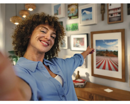 Vrouw wijst naar ingelijste foto in een heldere woonkamer
