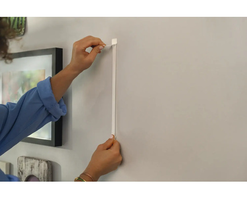 Persoon bevestigt een fotolijst aan de muur