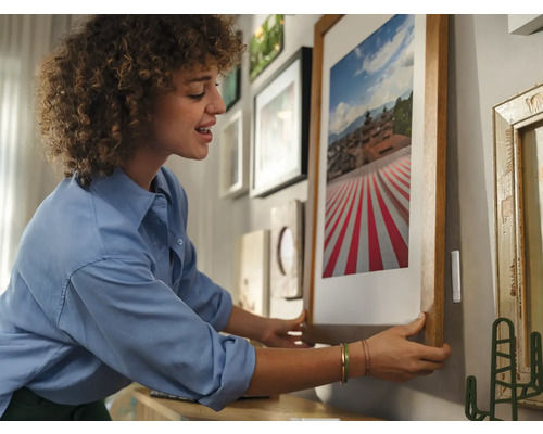Vrouw hangt ingelijste foto aan de muur