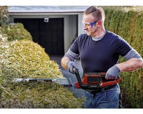 Man snoeit haag met een elektrische heggenschaar van Einhell.