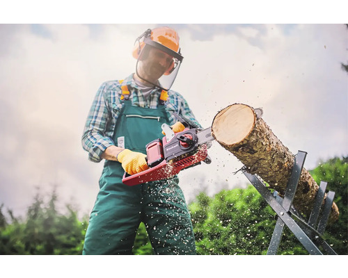 Man met veiligheidskleding zaagt een boomstam op een zaagbok met een Einhell kettingzaag