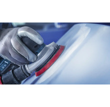 Ambachtsman schuurt oppervlak met een excentrische schuurmachine