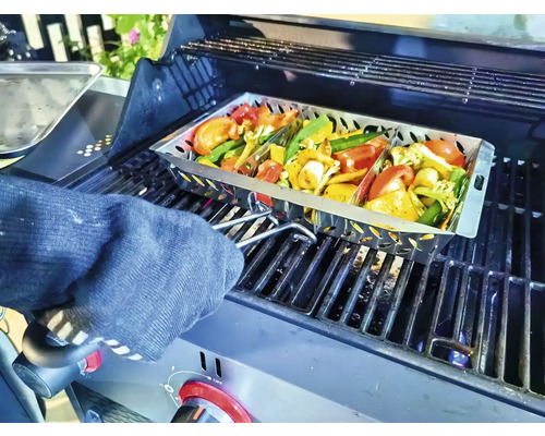 Groenten in een grillpan op een barbecue, vastgehouden door iemand met een ovenwant
