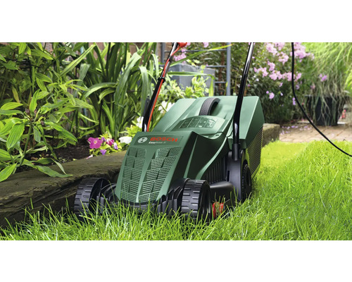 Grasmaaier in gebruik in de tuin tussen de planten