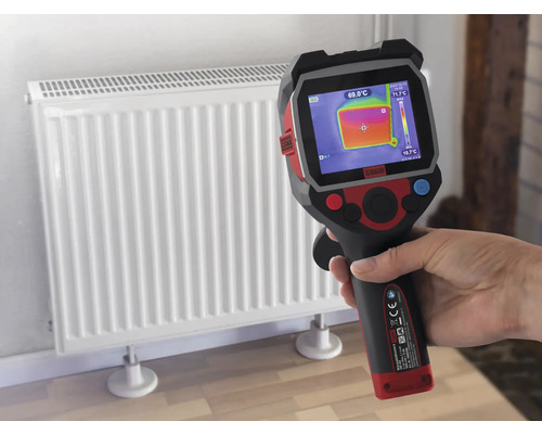 Een hand houdt een warmtebeeldcamera voor een radiator om de temperatuur te meten.