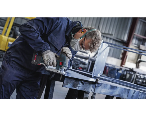 Een vakman snijdt metaal met een decoupeerzaag in een werkplaats.