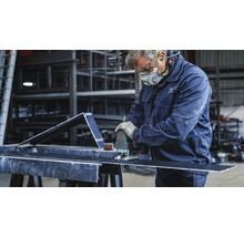 Een vakman snijdt een stuk metaal met een decoupeerzaag. Hij draagt beschermende kleding.