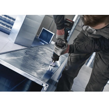 Ambachtsman snijdt een metalen plaat met een knabbelschaar.