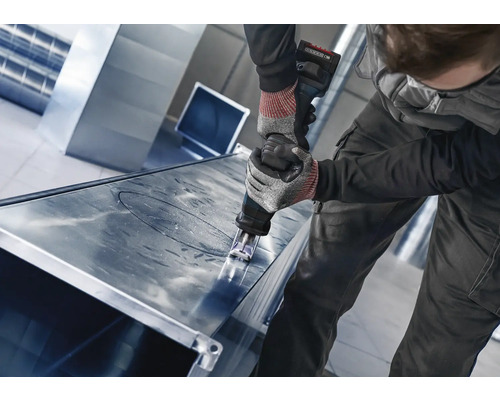 Ambachtsman snijdt een metalen plaat met een knabbelschaar.