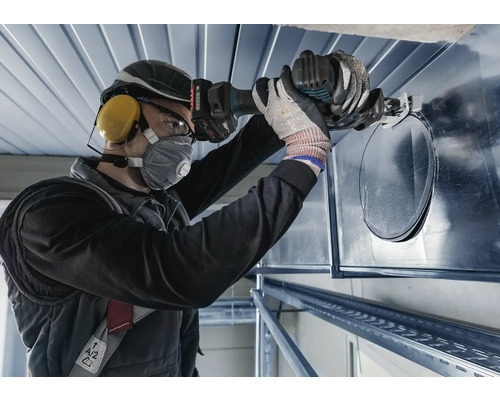 Een persoon gebruikt een knabbelschaar om een gat in een ventilatiekanaal te knippen.