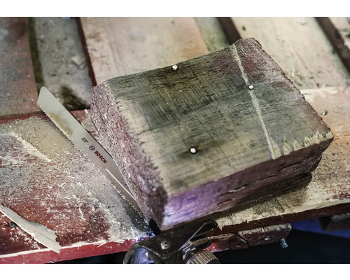 Een stuk hout met een decoupeerzaag en een Bosch zaag
