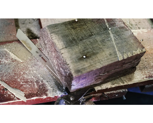 Houtstuk met metalen zaag en Bosch Logo.