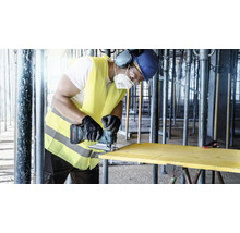 Vakman zaagt een houten plank met een draadloze decoupeerzaag op een bouwplaats.