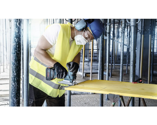 Vakman zaagt een houten plank met een draadloze decoupeerzaag op een bouwplaats.