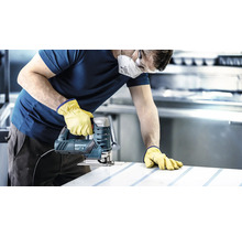 Ambachtsman met veiligheidsmasker, veiligheidsbril en handschoenen zaagt een werkstuk met een decoupeerzaag.