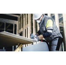 Een bouwvakker snijdt een gipsplaat met een decoupeerzaag op een bouwplaats