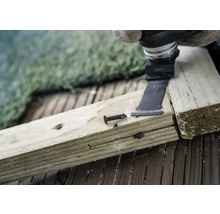 Oscillerend elektrisch gereedschap snijdt een spijker in een houten plank.