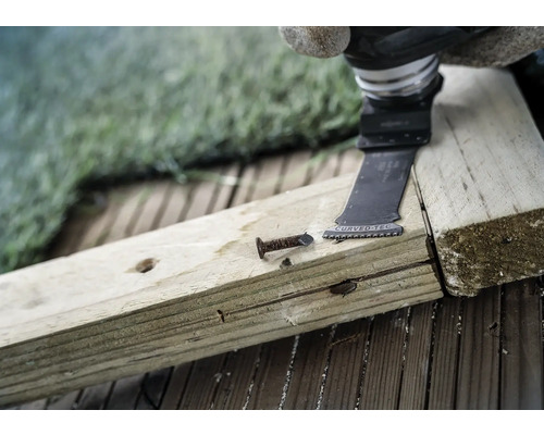 Oscillerend elektrisch gereedschap snijdt een spijker in een houten plank.