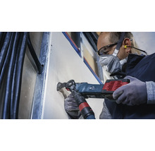 Ambachtsman snijdt met een multifunctioneel gereedschap een opening in een gipsplaatwand.
