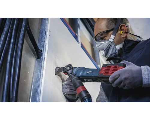 Ambachtsman snijdt met een multifunctioneel gereedschap een opening in een gipsplaatwand.