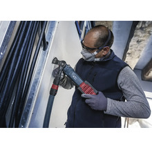 Een vakman gebruikt een multifunctioneel gereedschap om in een muur te snijden