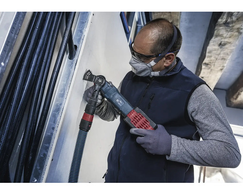 Een vakman gebruikt een multifunctioneel gereedschap om in een muur te snijden