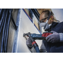 Ambachtsman zaagt met een multifunctioneel gereedschap een gat in een gipsplatenwand