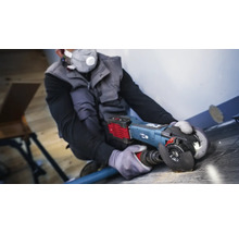 Ambachtsman gebruikt een haakse slijper met stofafzuiging op een houten vloer