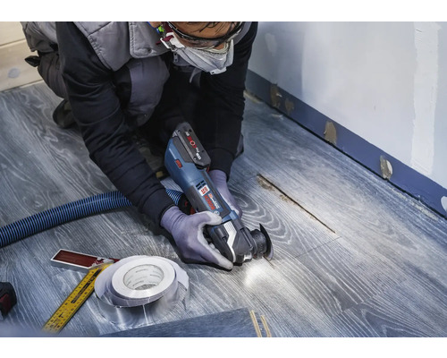 Ambachtsman gebruikt multifunctioneel gereedschap op laminaatvloer voor renovatiewerkzaamheden.