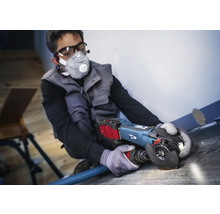 Man werkt met een haakse slijper op een vloerbedekking, persoonlijke beschermingsmiddelen zijn aanwezig