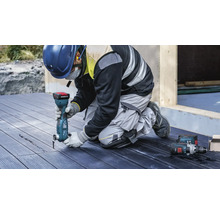 Een vakman gebruikt een multifunctioneel gereedschap op een houten terras. Ook is er persoonlijke beschermingsmiddelen aanwezig.