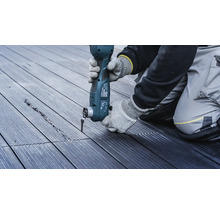 Een persoon werkt met een multifunctioneel gereedschap op een houten terras.