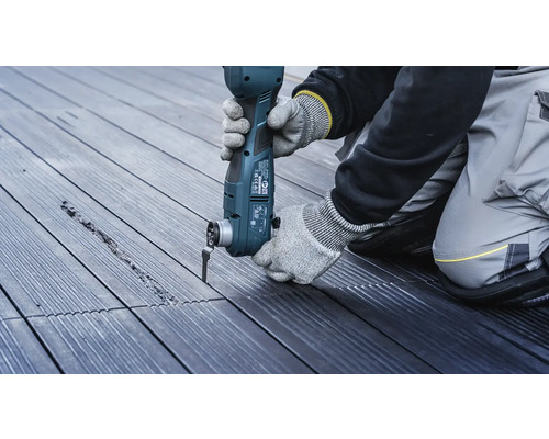 Een persoon werkt met een multifunctioneel gereedschap op een houten terras.