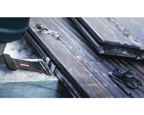 Gedetailleerde opname van een zaagblad dat dakpannen met bevestigingsclips zaagt