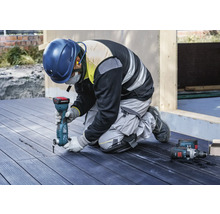 Ambachtsman knielt op een terras en werkt met een multifunctioneel gereedschap