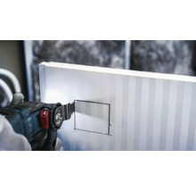 Een oscillerende zaag snijdt in een isolatieplaat.