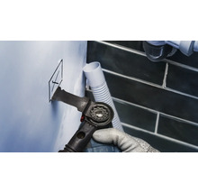 Ambachtsman snijdt een gat in een muur met een multifunctioneel gereedschap