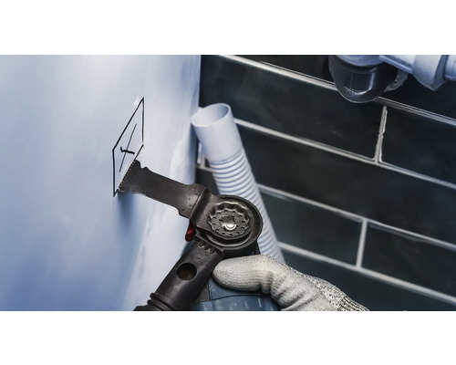 Ambachtsman snijdt een gat in een muur met een multifunctioneel gereedschap