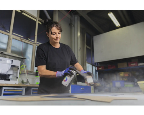 Vrouw spuit verf op een werkstuk met een spuitbus.