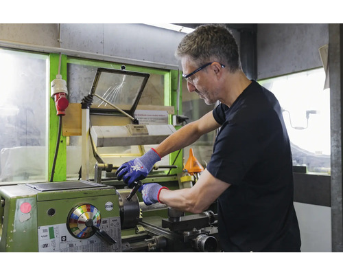 Een man werkt aan een draaibank in een werkplaats.