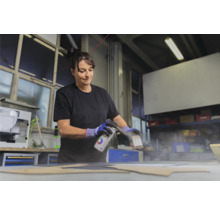 Vrouw spuit verf op een werkstuk met een spuitbus.