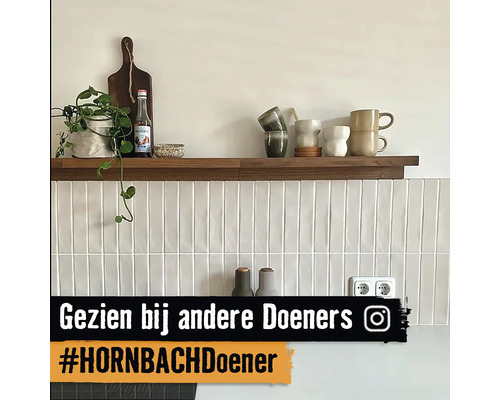 Plank met decoratie aan een wand met witte, langwerpige tegels