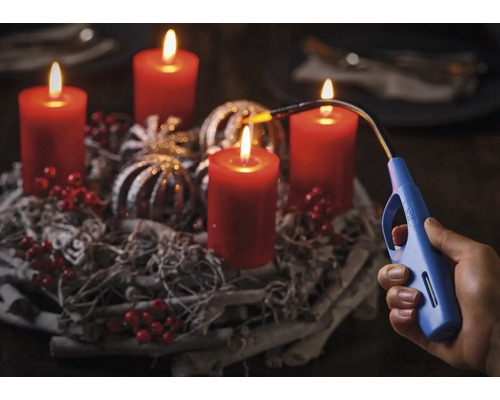 Advent krans met vier brandende kaarsen en een staafaansteker in een hand