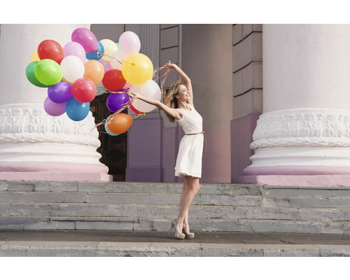 Vrouw met veel ballonnen voor een gebouw