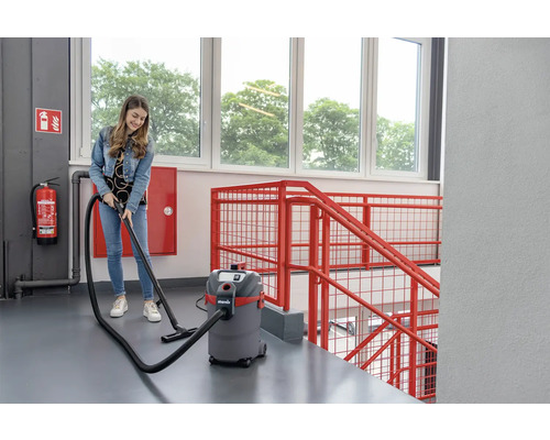 Een vrouw gebruikt een nat- en droogzuiger in een trappenhuis.