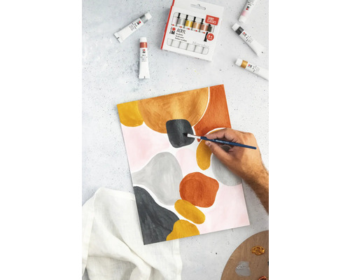 Een persoon schildert een abstract kunstwerk op papier met acrylverf, omringd door tubes verf en een verfdoos.