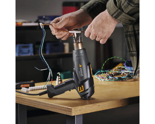 Een persoon gebruikt een Steinel heteluchtpistool om kabels te bewerken.