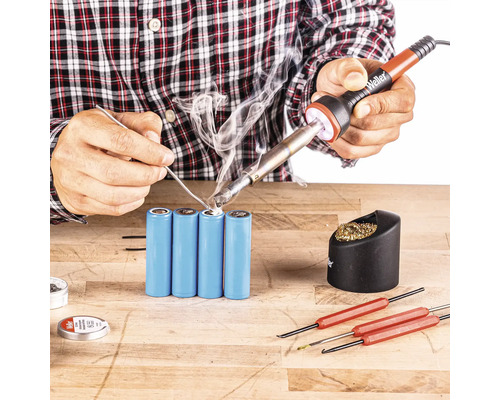 Batterijen solderen met soldeerbout, soldeertin en gereedschap op een werkbank.