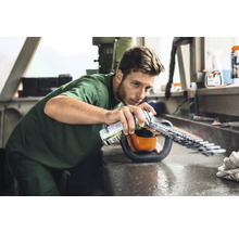 Man spuit onderhoudsspray op een heggenschaar om de messen te onderhouden.